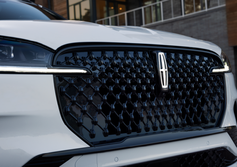 The black grille of a white 2025 Lincoln Aviator® SUV is shown with its fog lights on. | Midland Lincoln in Midland MI
