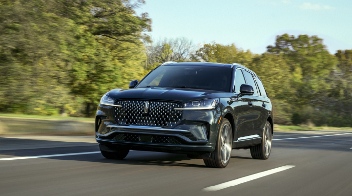 A 2025 Lincoln Black Label Aviator® SUV is being driven down a road lined with trees. | Midland Lincoln in Midland MI