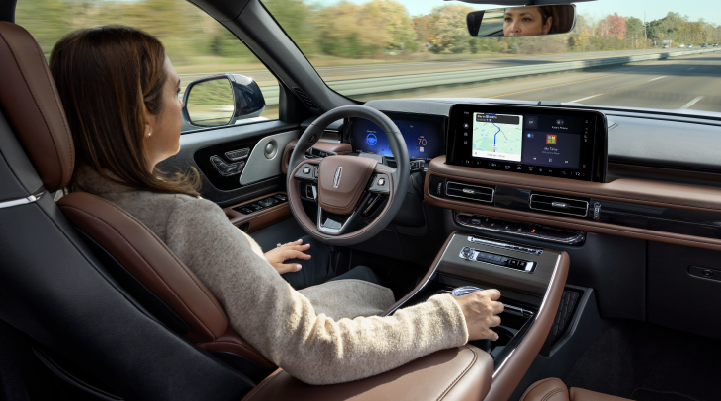 A woman is seen sitting in the driver’s seat of her 2025 Lincoln Aviator® SUV with her hands off the steering wheel. | Midland Lincoln in Midland MI
