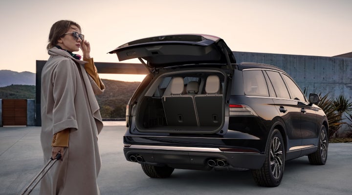 A woman approaches a 2026 Lincoln Aviator® SUV with its rear liftgate open. | Midland Lincoln in Midland MI
