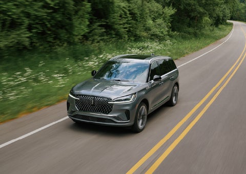 A 2027 Lincoln Aviator® SUV is being driven down a road. | Midland Lincoln in Midland MI