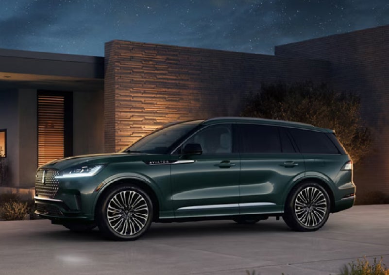 A green 2027 Lincoln Aviator® SUV is parked outside a contemporary home. | Midland Lincoln in Midland MI
