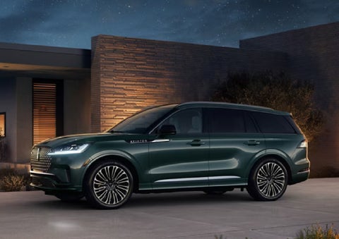 A green 2027 Lincoln Aviator® SUV is parked outside a contemporary home. | Midland Lincoln in Midland MI