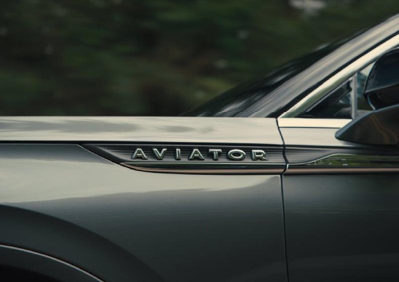 The driver’s side door and fender badging of a gray 2027 Lincoln Aviator® SUV are showcased. | Midland Lincoln in Midland MI
