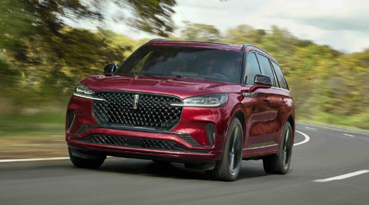 A 2027 Lincoln Aviator® SUV is being driven on a country road | Midland Lincoln in Midland MI
